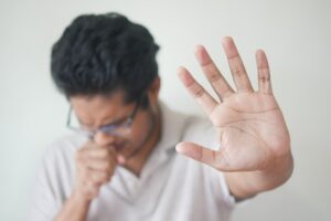 Man sneezing and holding his hand in the air