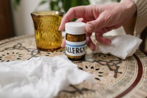 Person taking their allergy medication from a wooden table
